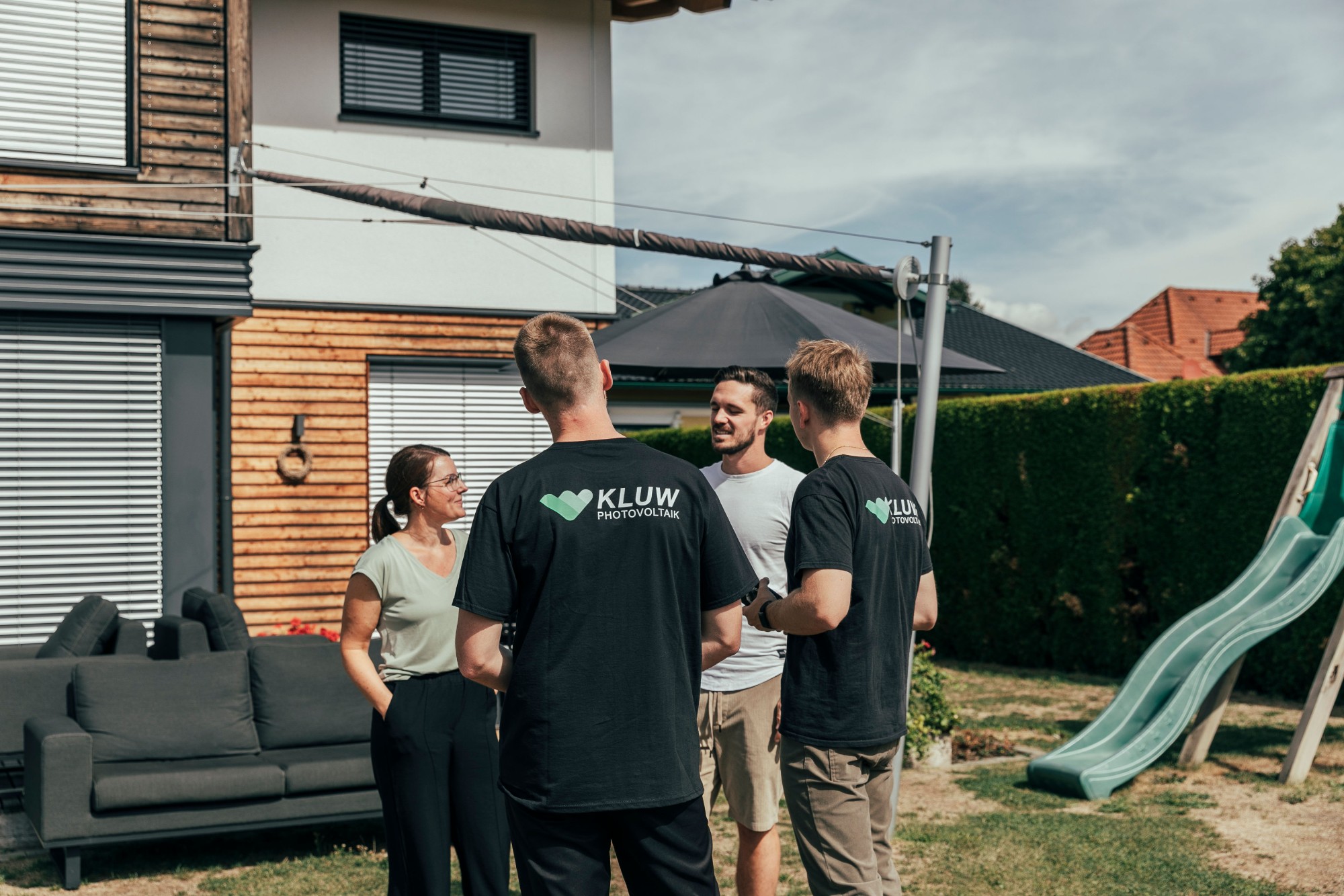 Zwei KLUW-Mitarbeiter im Gespräch mit einem Paar im Garten vor dessen Haus
