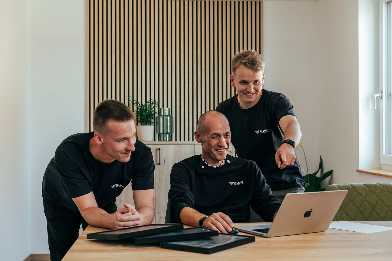Drei KLUW-Mitarbeiter sehen sich gemeinsam am Laptop eine Förderabwicklung an