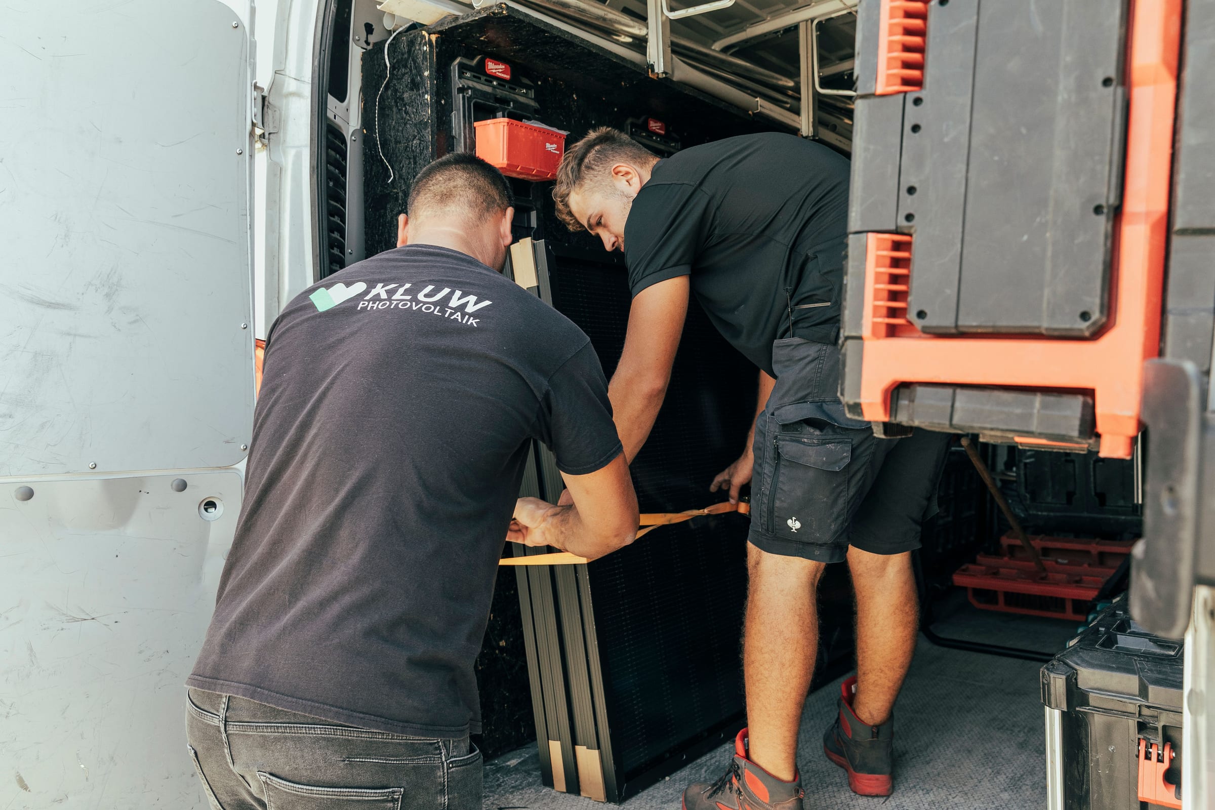 Zwei KLUW-Monteure verzurren Module im Firmenfahrzeug