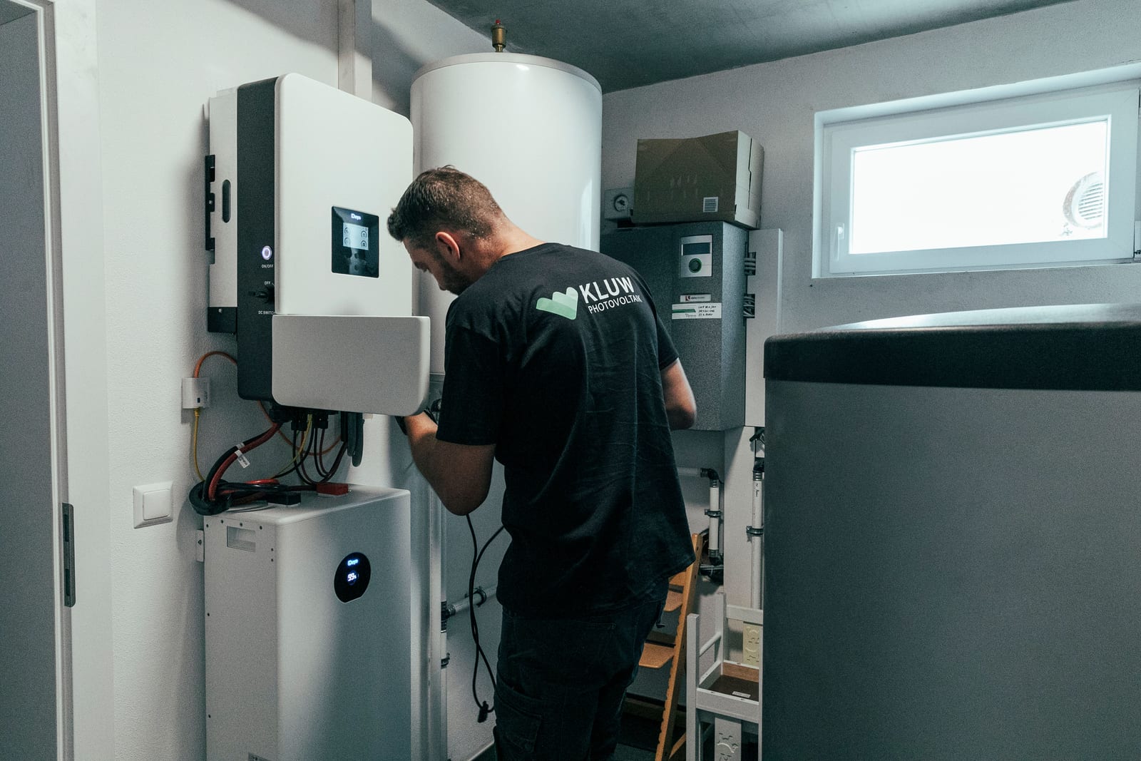 KLUW-Monteur montiert Batteriespeicher und Wechselrichter im Technikraum